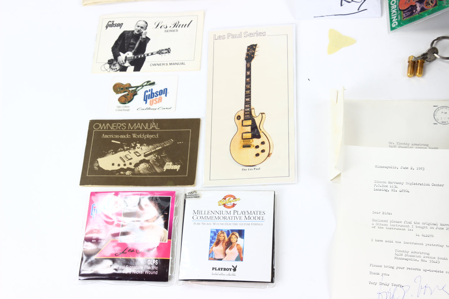 Collection of Gibson guitar memorabilia including owner's manual, posters, and a Playboy magazine.