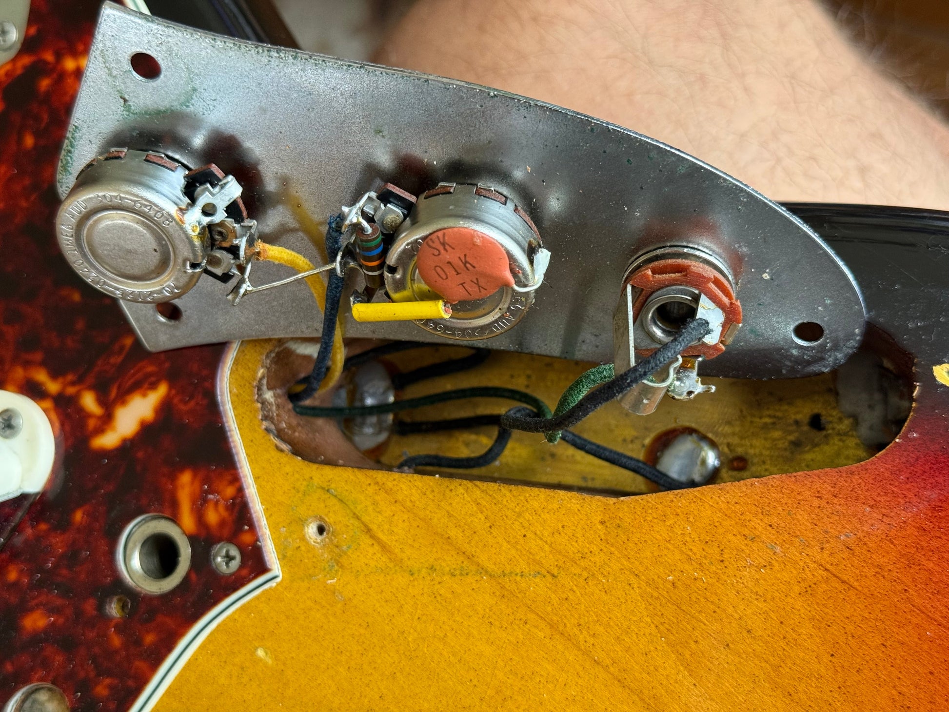 Close-up of a guitar's control panel with wiring and potentiometers.