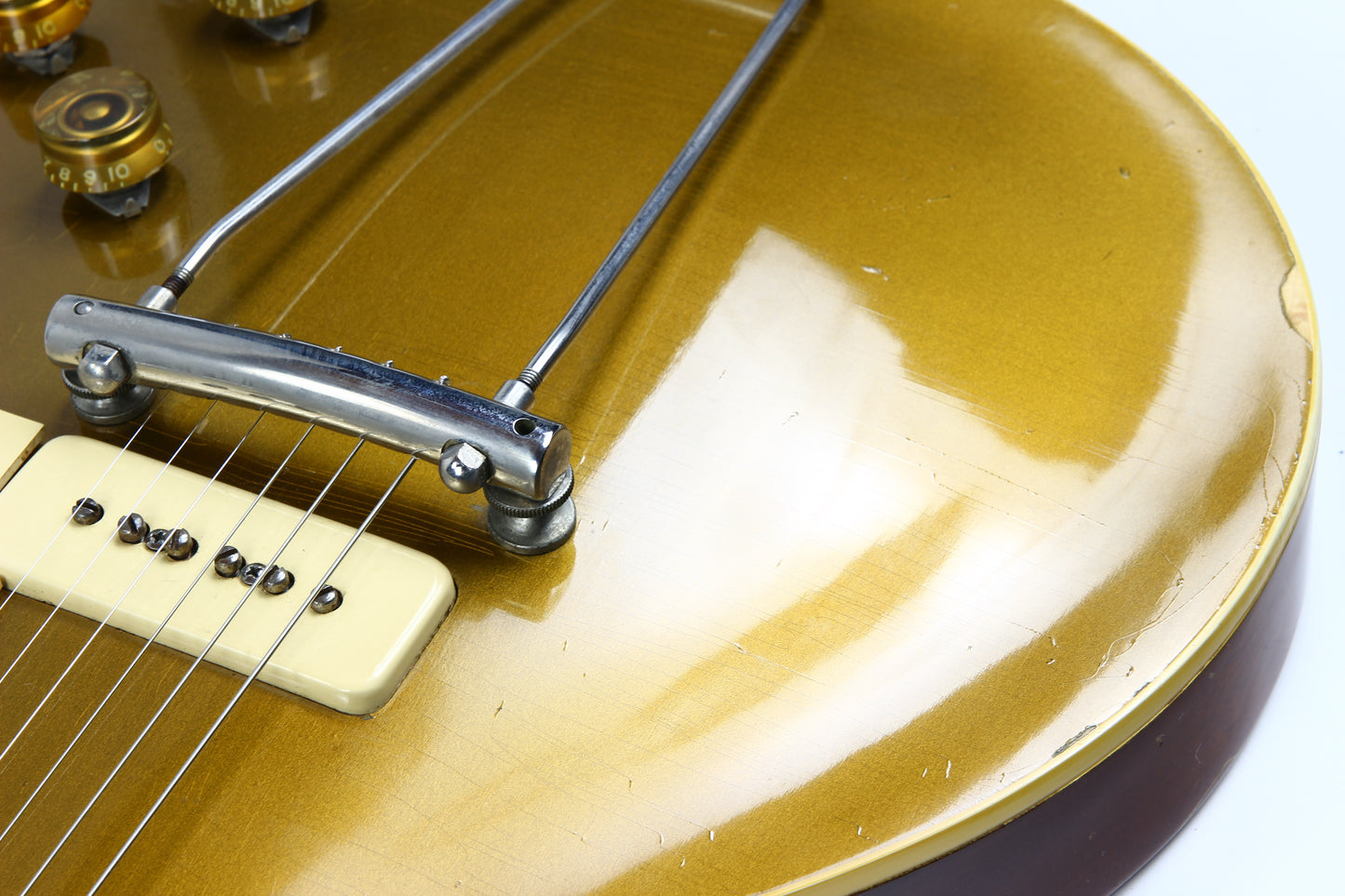 Close-up of a guitar's bridge and headstock with a white background